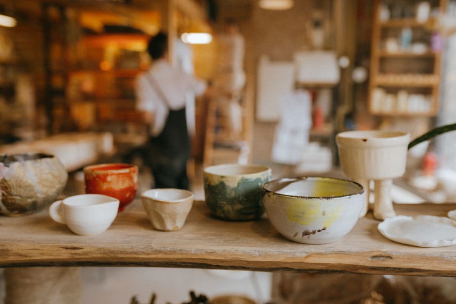 A collection of handcrafted ceramic bowls in a warm and rustic workshop setting.
