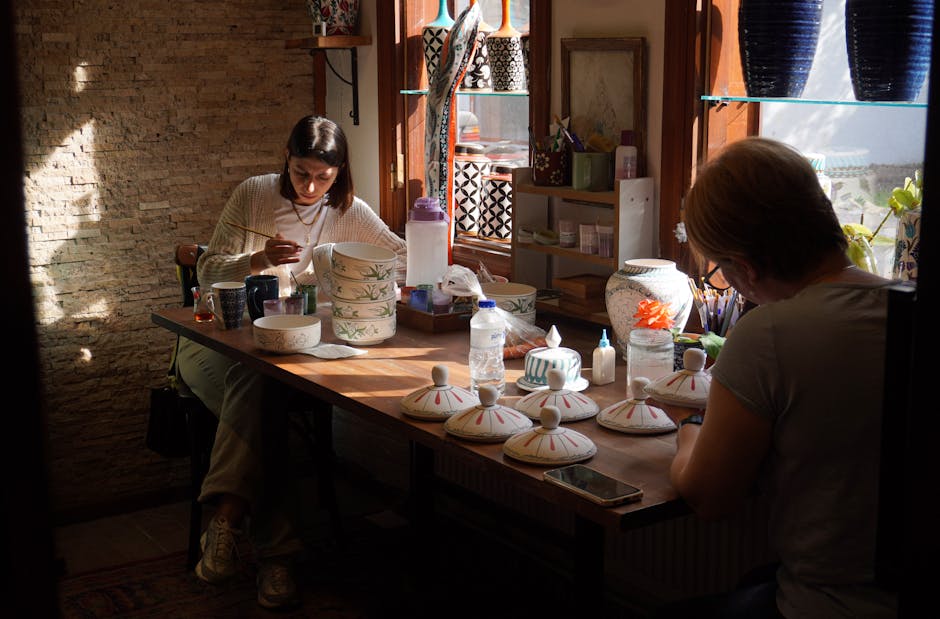 Two artisans focus on painting ceramic pieces in a sunlit studio in Bursa, Türkiye.